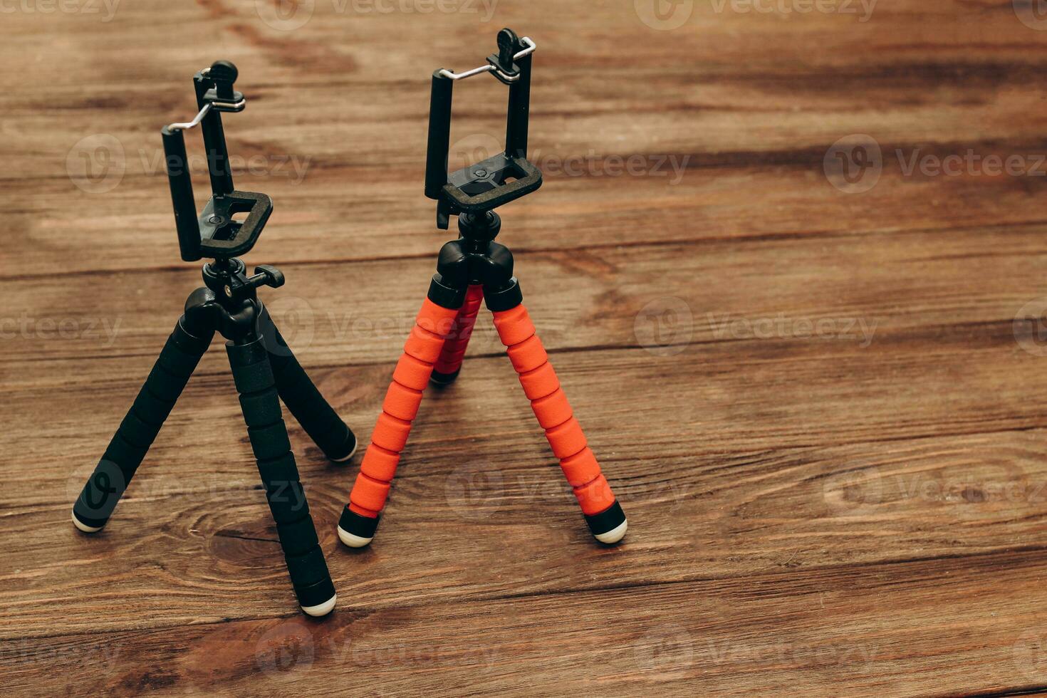 Two manual tripod monopods for a phone or a small camera on a wooden table. photo