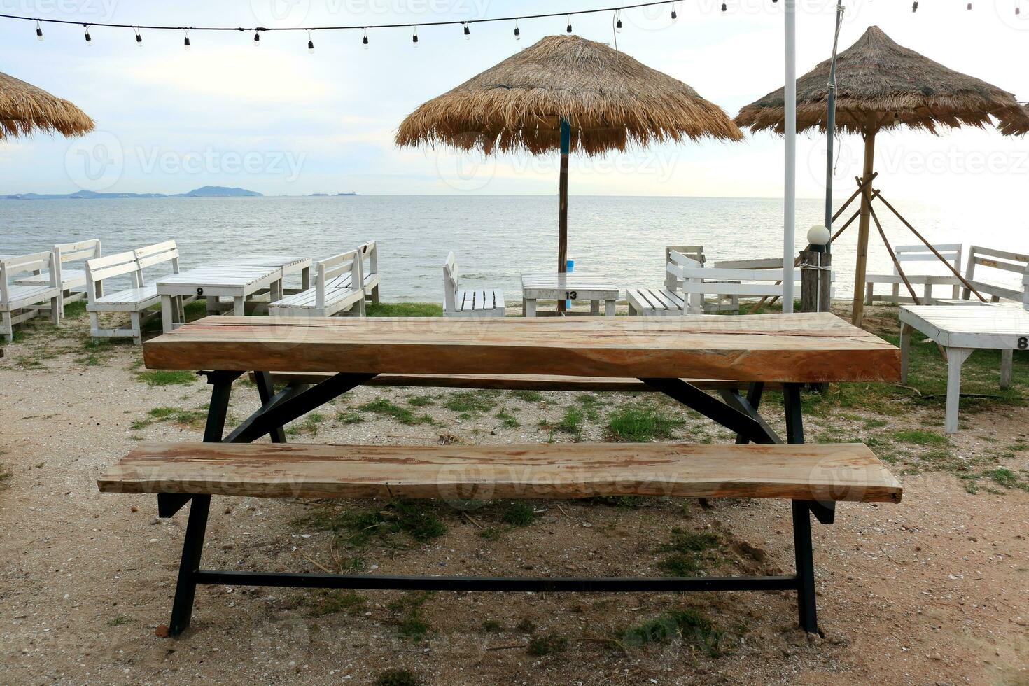 marrón madera mesa y banco en arena con mar y brillante cielo fondo, tailandia foto
