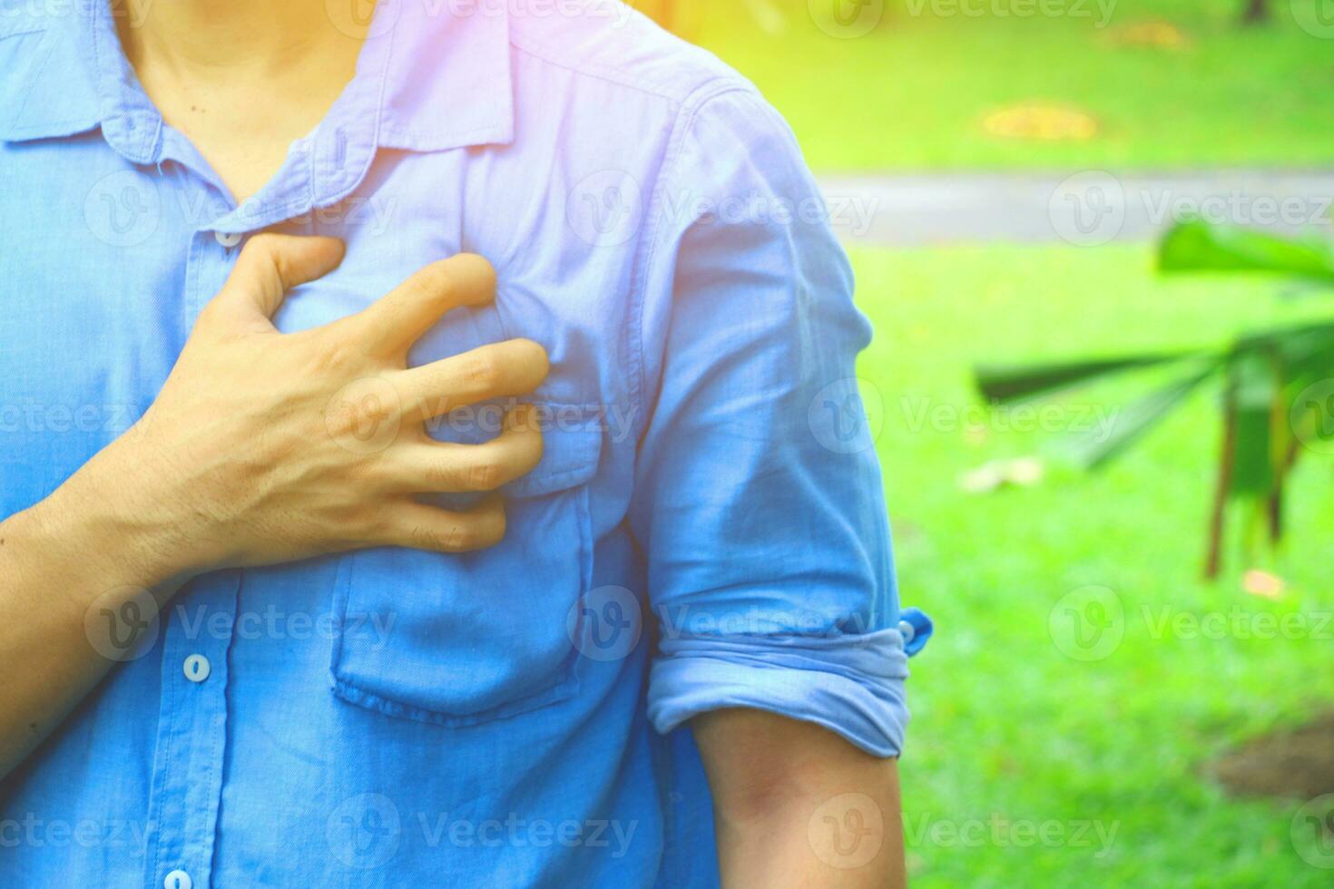 a man is holding his chest in the grass photo