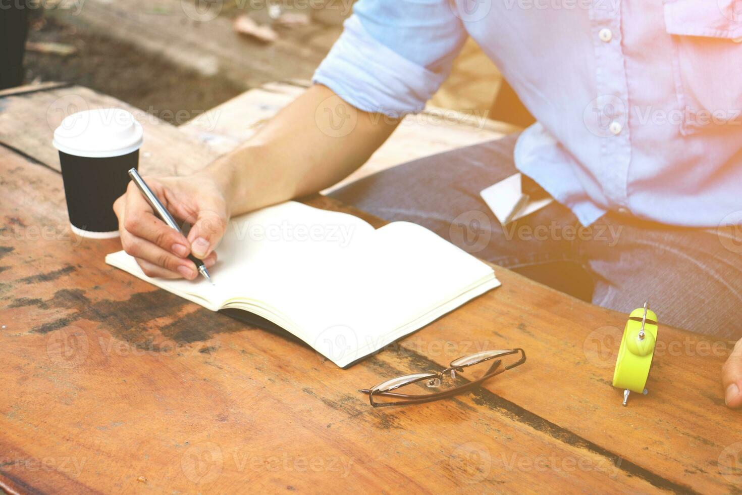 a man sitting at a table with a notebook and a cup of coffee photo