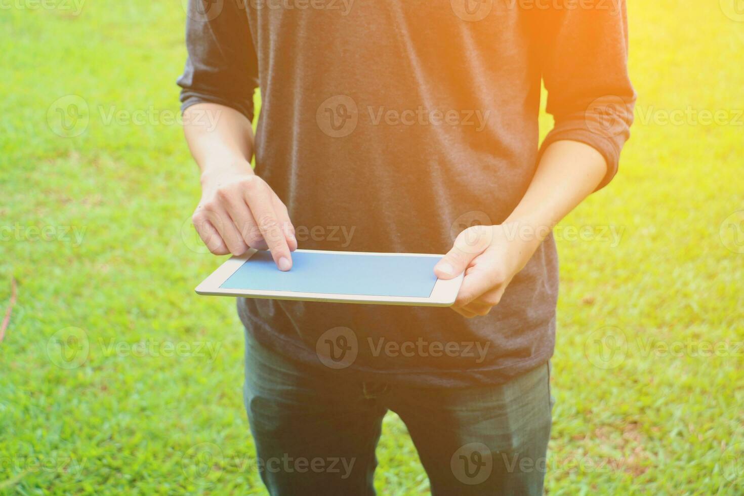 a man holding a tablet computer in the grass photo