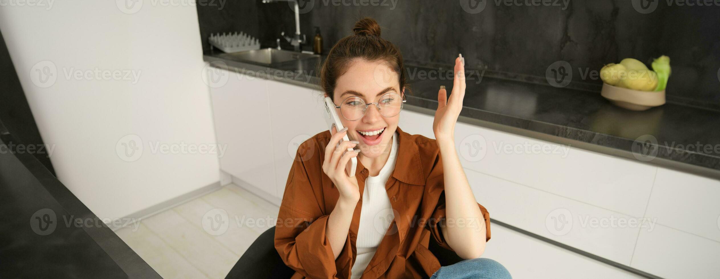 Portrait of happy modern woman, answer phone call and celebrating, looking excited, triumphing from great news, talking on smartphone photo