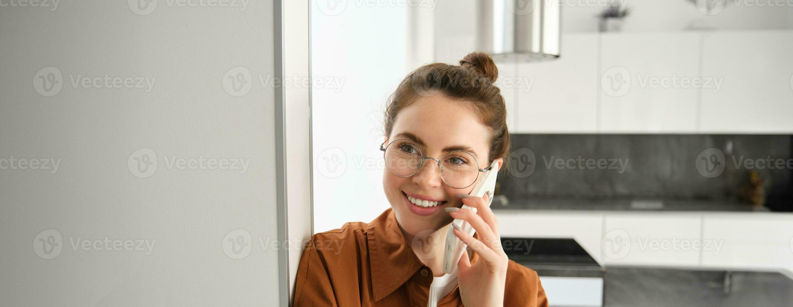 retrato de contento mujer a hogar, respuestas teléfono llamar, hablando en móvil, participación teléfono inteligente y sonriente foto