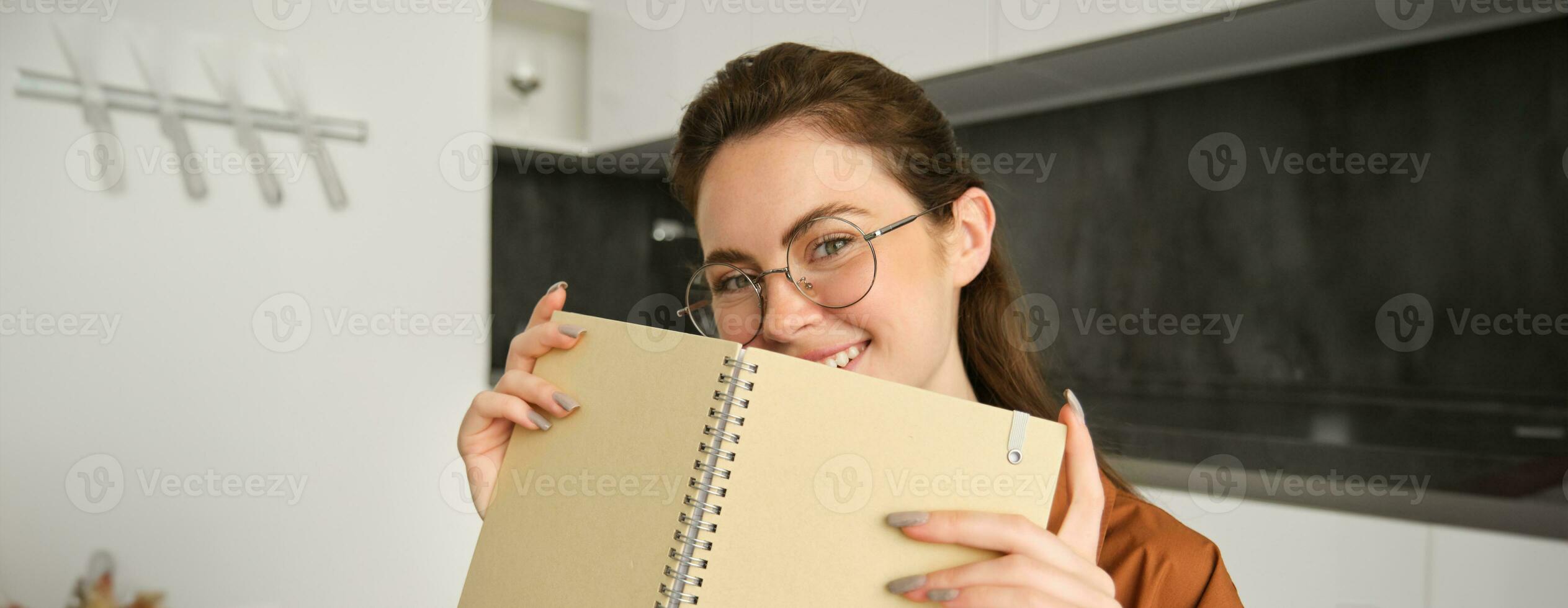 Close up portrait of young woman smiling, holding notebook, showing her planner photo