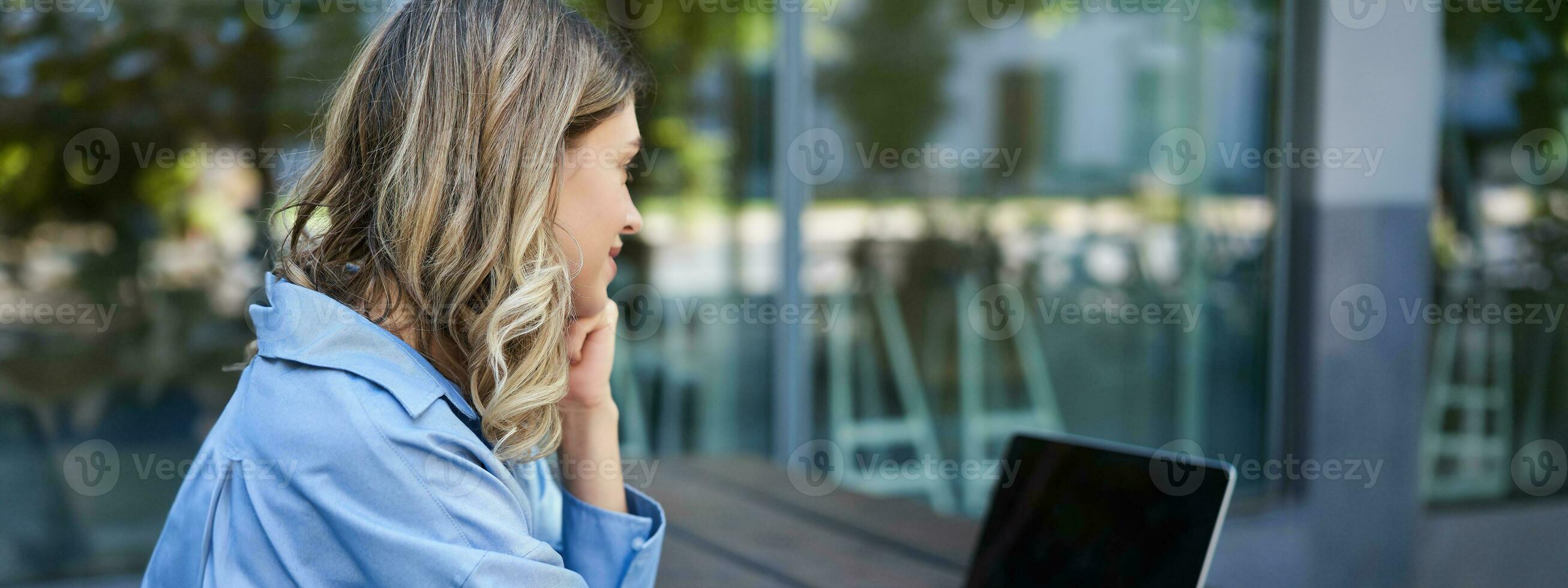 cerca arriba retrato de mujer estudiante atender en línea curso clases, sentado fuera de en Fresco aire con ordenador portátil y tomando notas mujer de negocios vídeo charla en computadora foto