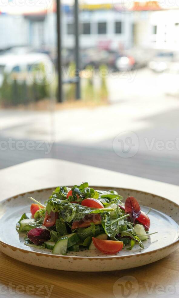 Fresco ensalada con Rúcula, Cereza Tomates, pepinos en cafetería mesa. foto