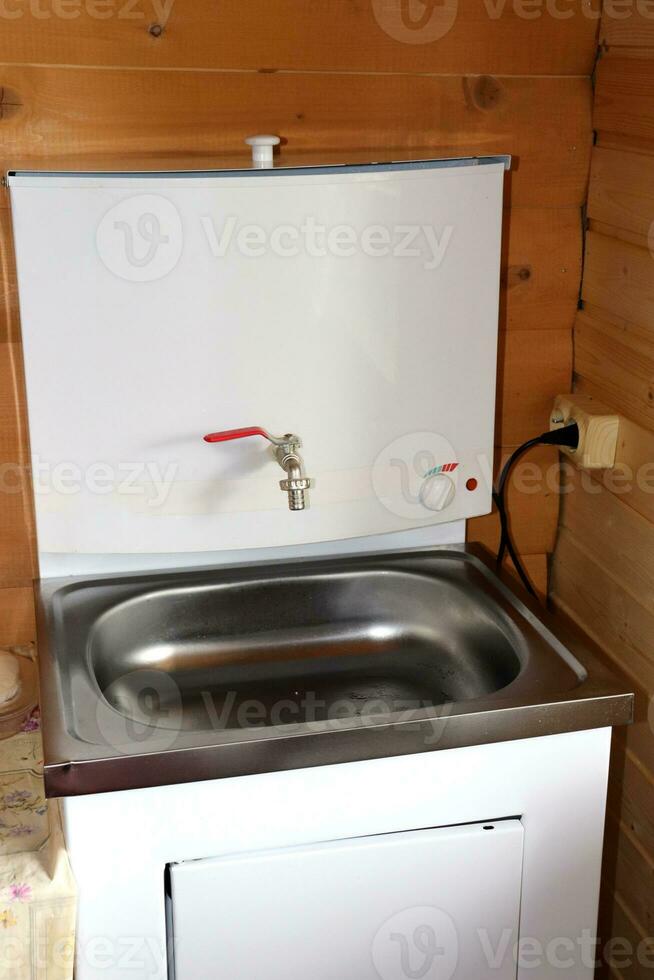 Metal electric washbasin for hand hygiene and washing dishes in a rural house. Vertical photo, close-up photo