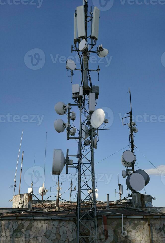 telecomunicación antena con múltiple satélite en contra el azul cielo foto