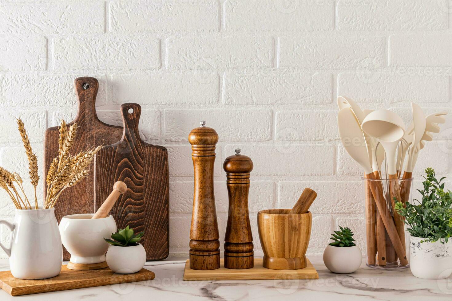 Various wooden kitchen utensils and cooking tools on the marble countertop. Front view. Stylish kitchen background. photo