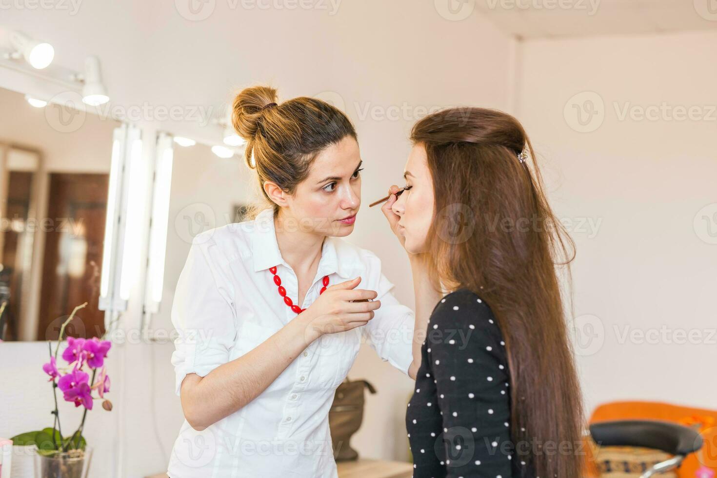 makeup artist applying make up on girl photo