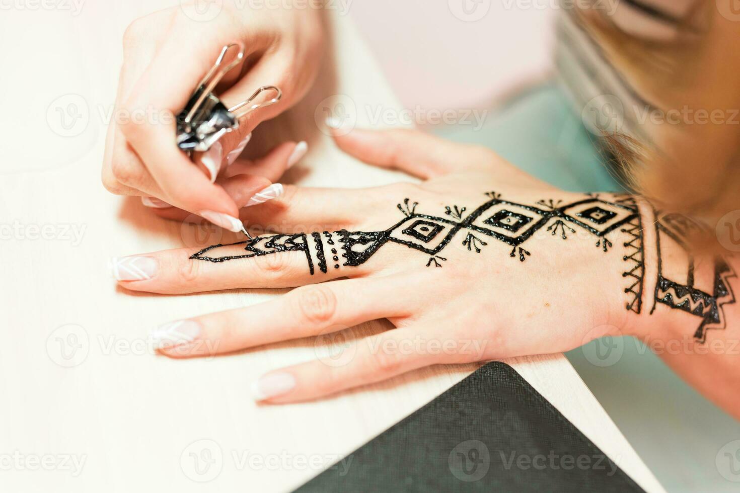 Artist applying henna tattoo on women hands. Mehndi is traditional Indian decorative art. Close-up photo