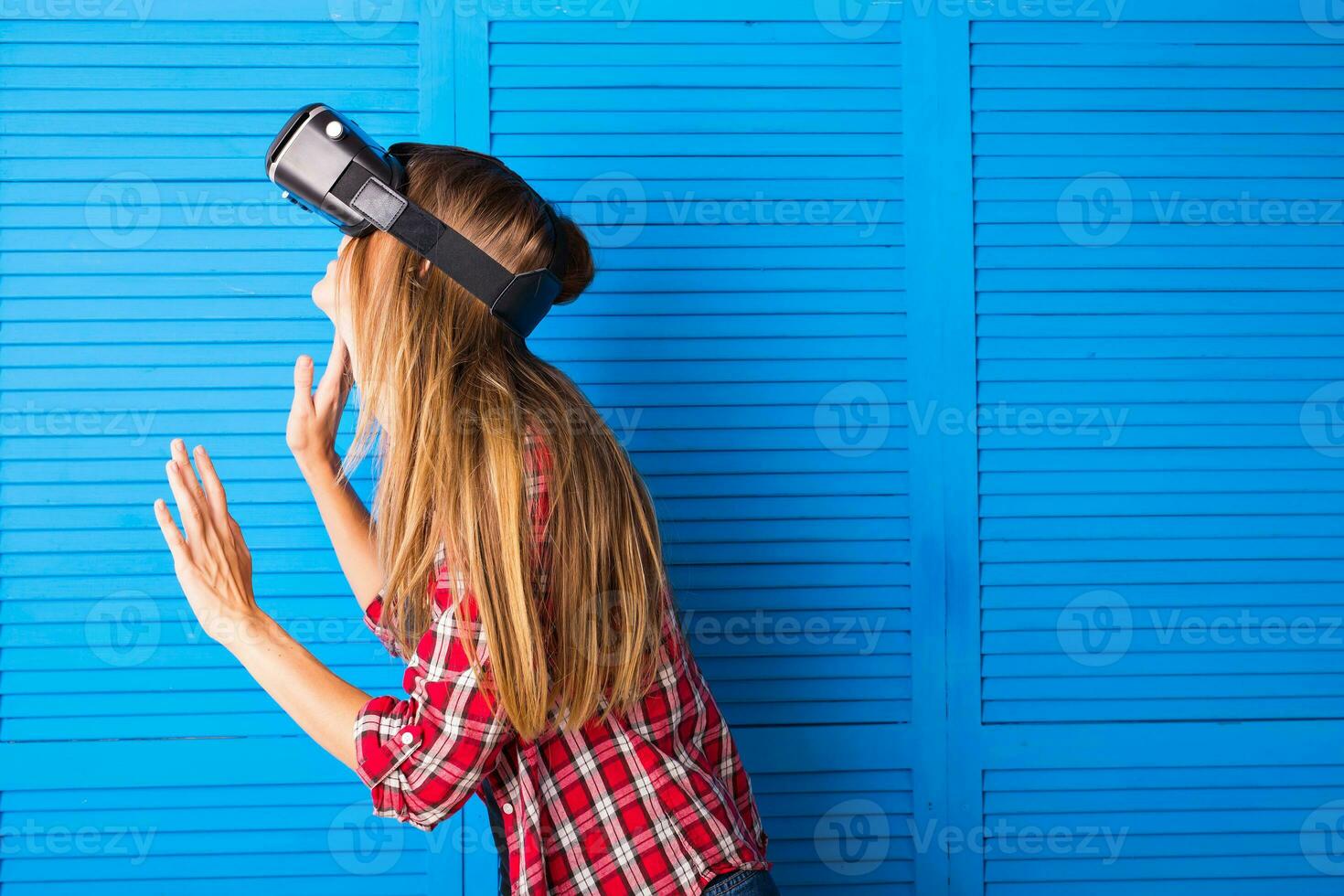 Happy woman getting experience using VR-headset glasses of virtual reality much gesticulating hands photo