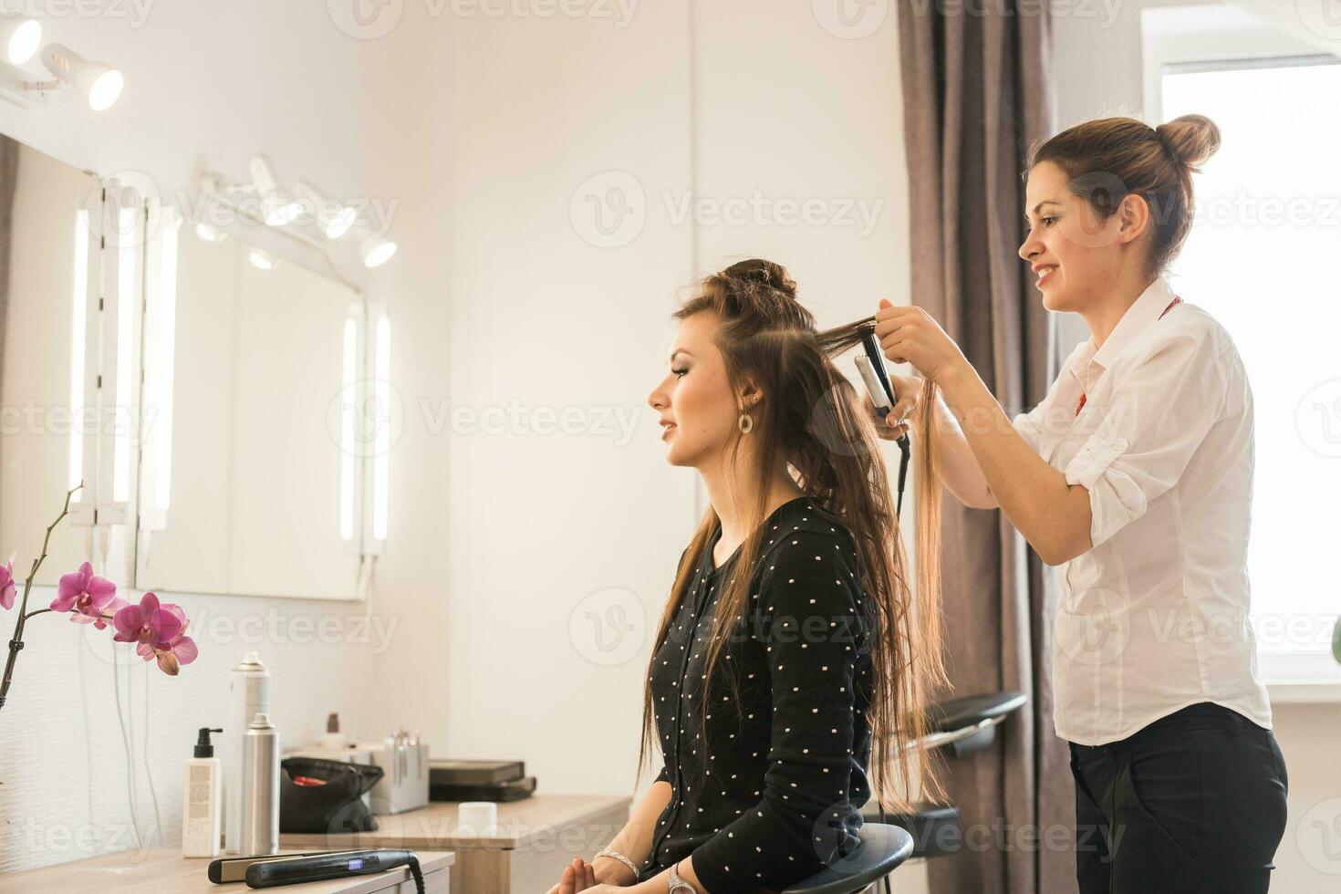 Woman at hairdresser with iron hair curler. photo