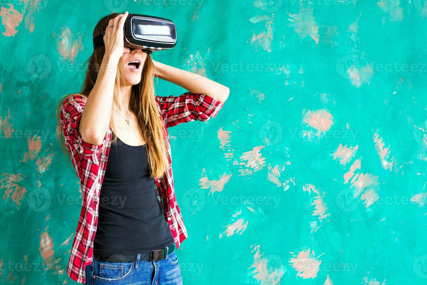 Happy woman getting experience using VR-headset glasses of virtual reality much gesticulating hands photo