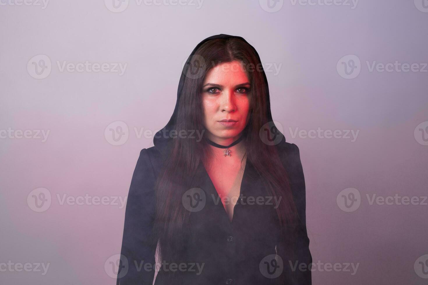 Gorgeous brunette with dark makeup. Halloween witch with smoke in studio photo