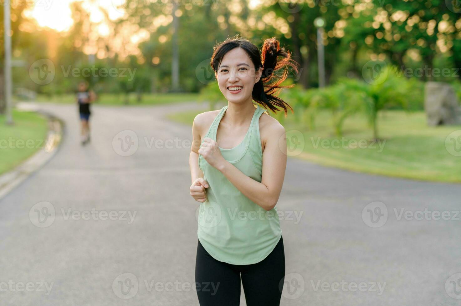 Fit Asian young woman jogging in park smiling happy running and enjoying a healthy outdoor lifestyle. Female jogger. Fitness runner girl in public park. healthy lifestyle and wellness being concept photo