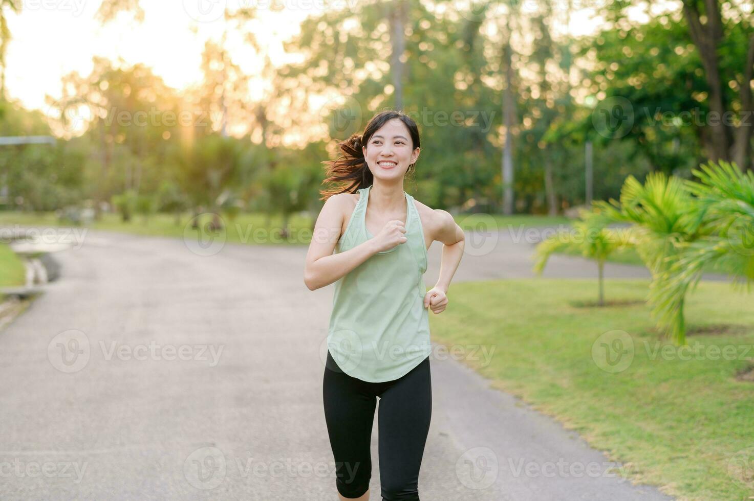 Fit Asian young woman jogging in park smiling happy running and enjoying a healthy outdoor lifestyle. Female jogger. Fitness runner girl in public park. healthy lifestyle and wellness being concept photo