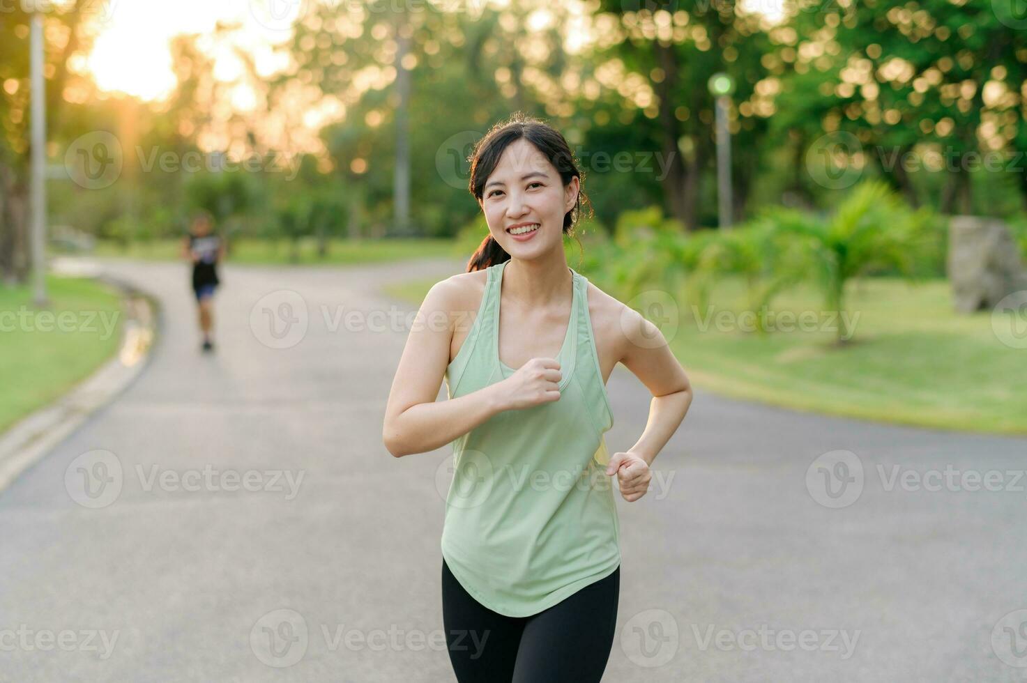 Fit Asian young woman jogging in park smiling happy running and enjoying a healthy outdoor lifestyle. Female jogger. Fitness runner girl in public park. healthy lifestyle and wellness being concept photo