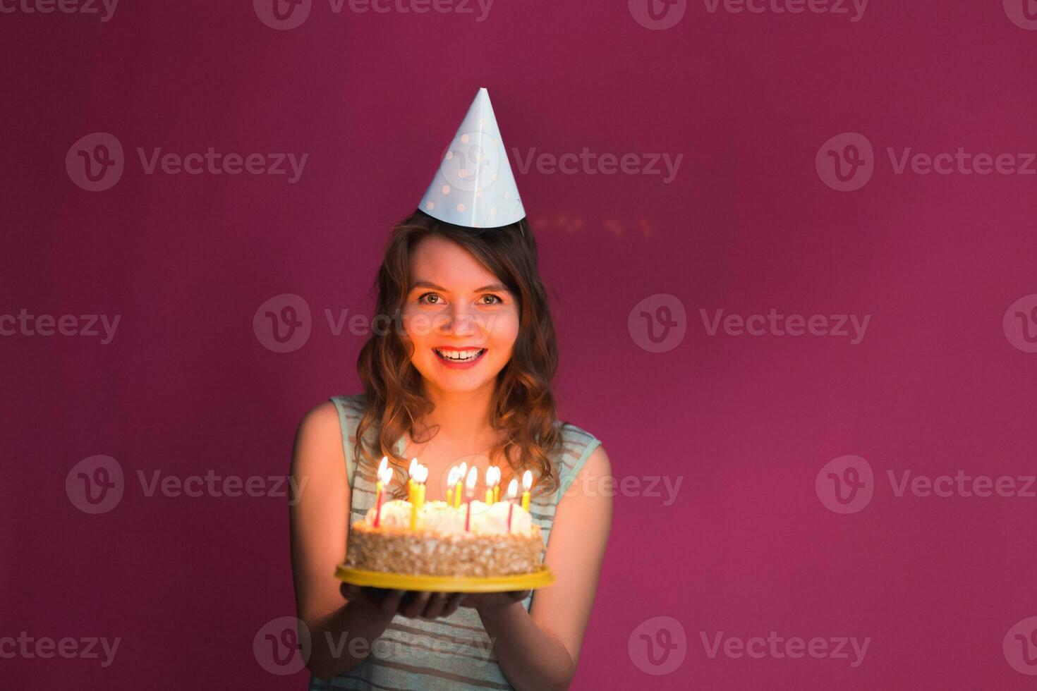 Portrait of joyful girl holding birthday cake and looking at camera at studio photo