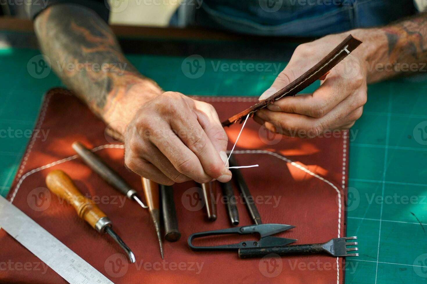 de cerca y cosecha manos de cuero artesano de coser un cuero marrón bolso para un cliente. foto