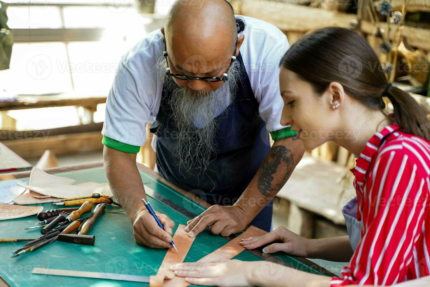 Team of leathers maker is drawing a design on leather sheet in leather workshop. photo