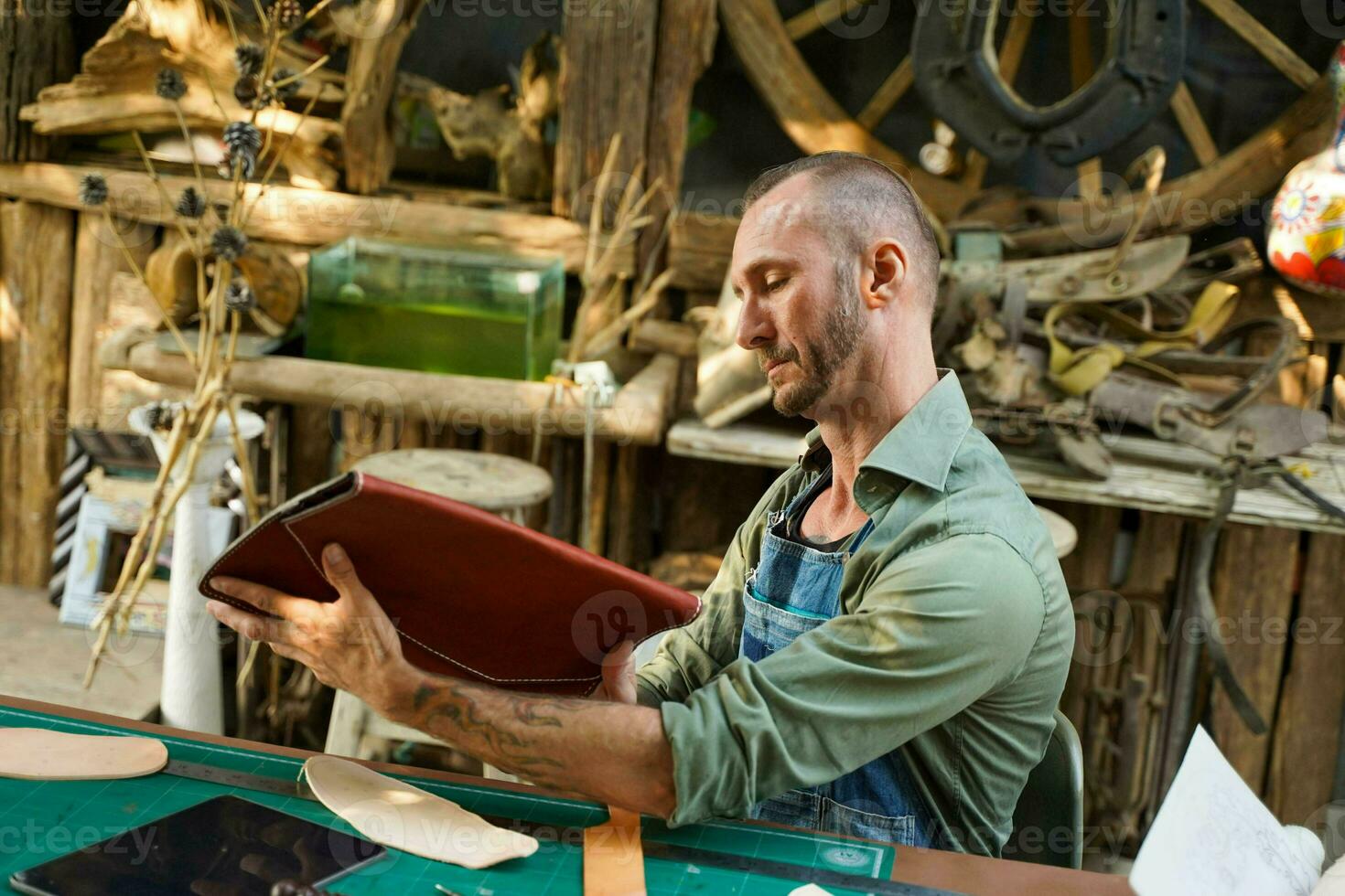 A leather craftsman looking and check the neatness of the leathers bag before sell to customer in workshop. photo