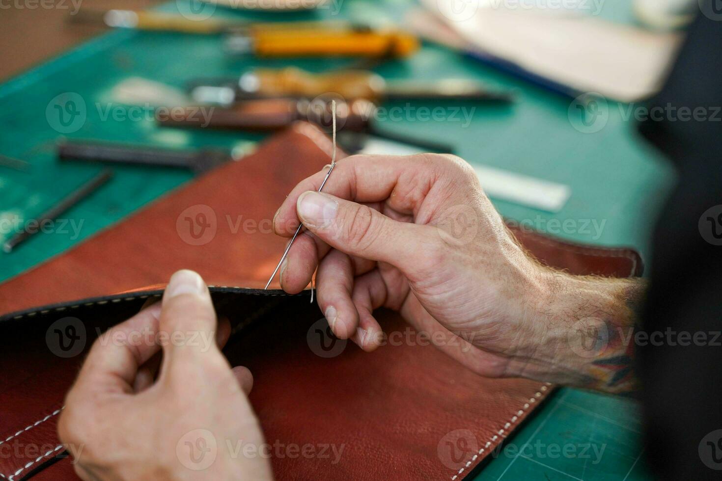 Closeup hand of leather craftsman is carefully to sew a leather bag for a customer., Leather craftsman concept. photo