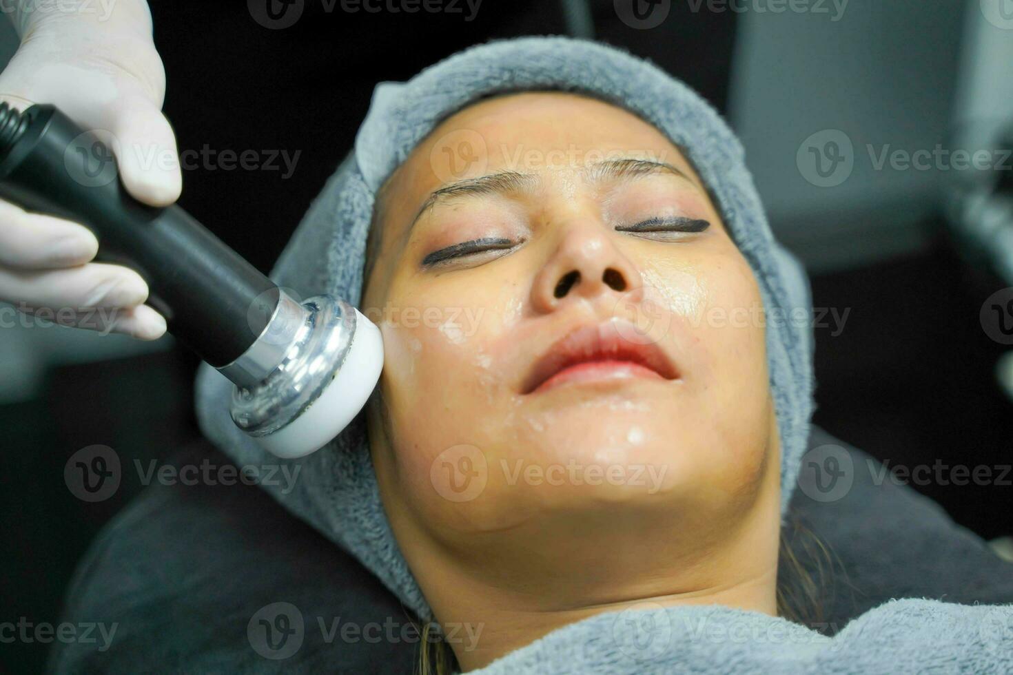 Closeup Asian beauty woman having therapy to stimulate facial skin and facial ultrasonic skincare treatment by professional cosmetologist wellbeing. photo