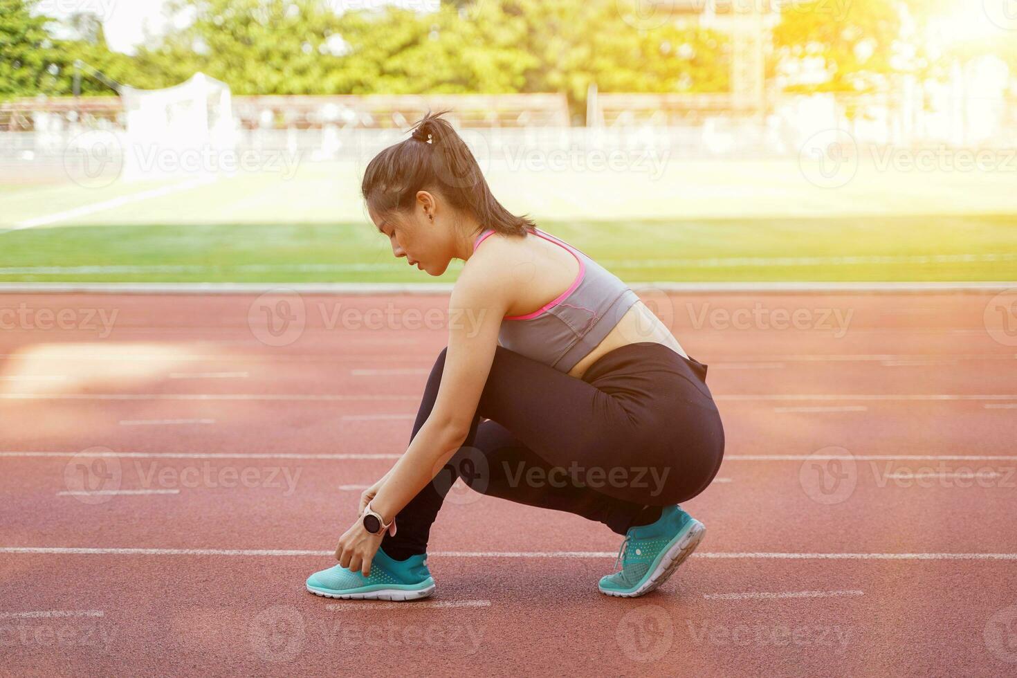 Young female get ready to exercise and jogging in the morning. at the football stadium with sunbeam and blurred background. photo