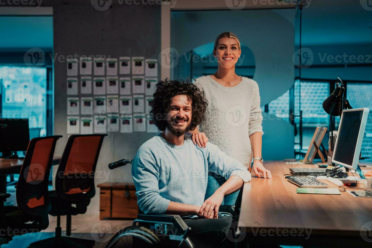 a man and woman in a wheelchair in an office photo