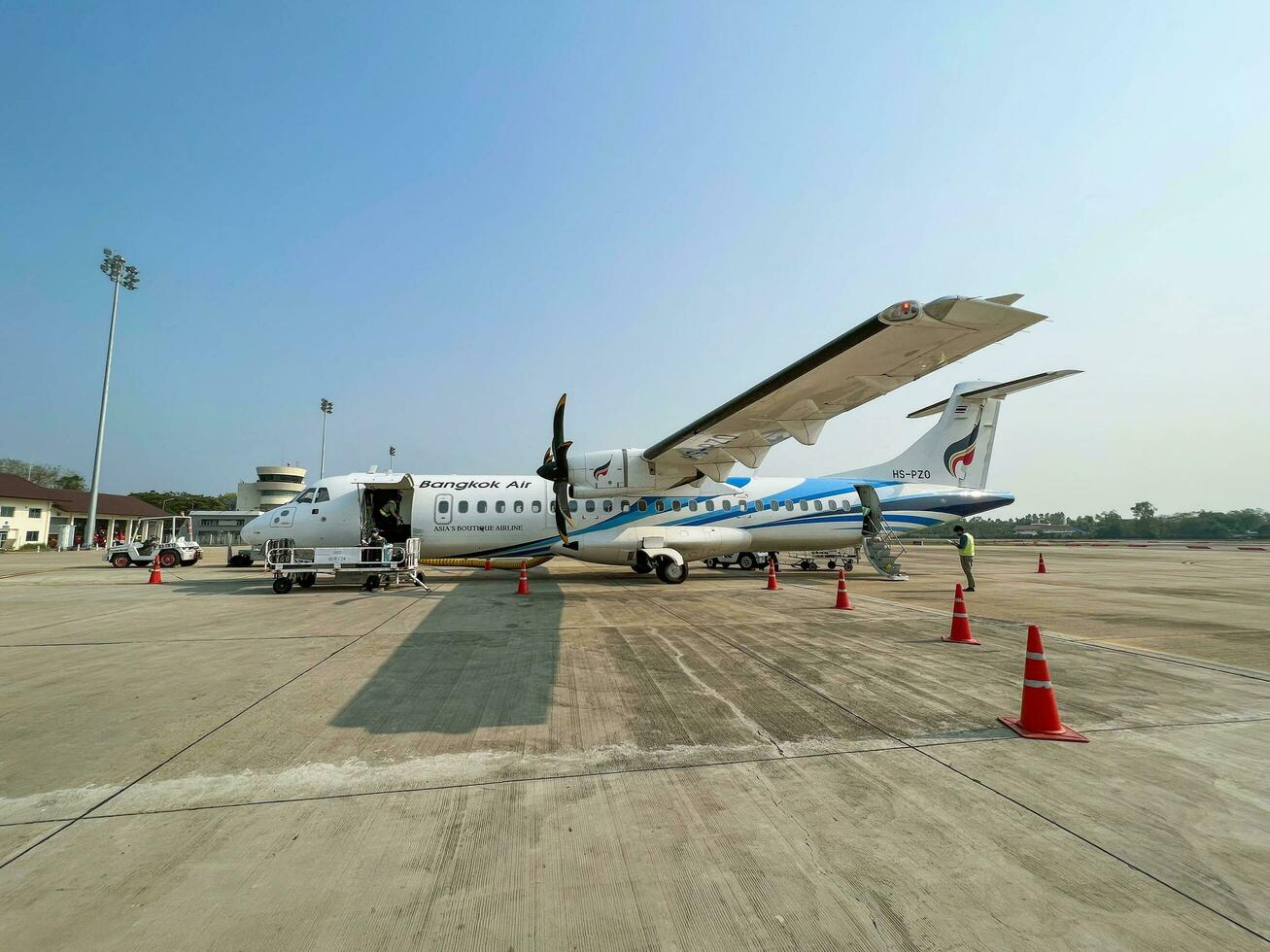 Lampang City, TH, 2022 - Small propeller plane of BANGKOK AIR with ground officer at the Lampang Airport. photo