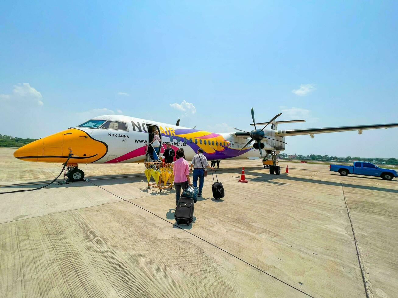 Lampang City, TH, 2022 - Perspective view of small propeller plane and  tourist walk up the plane of NOK AIR at the Lampang Airport to Bangkok. photo