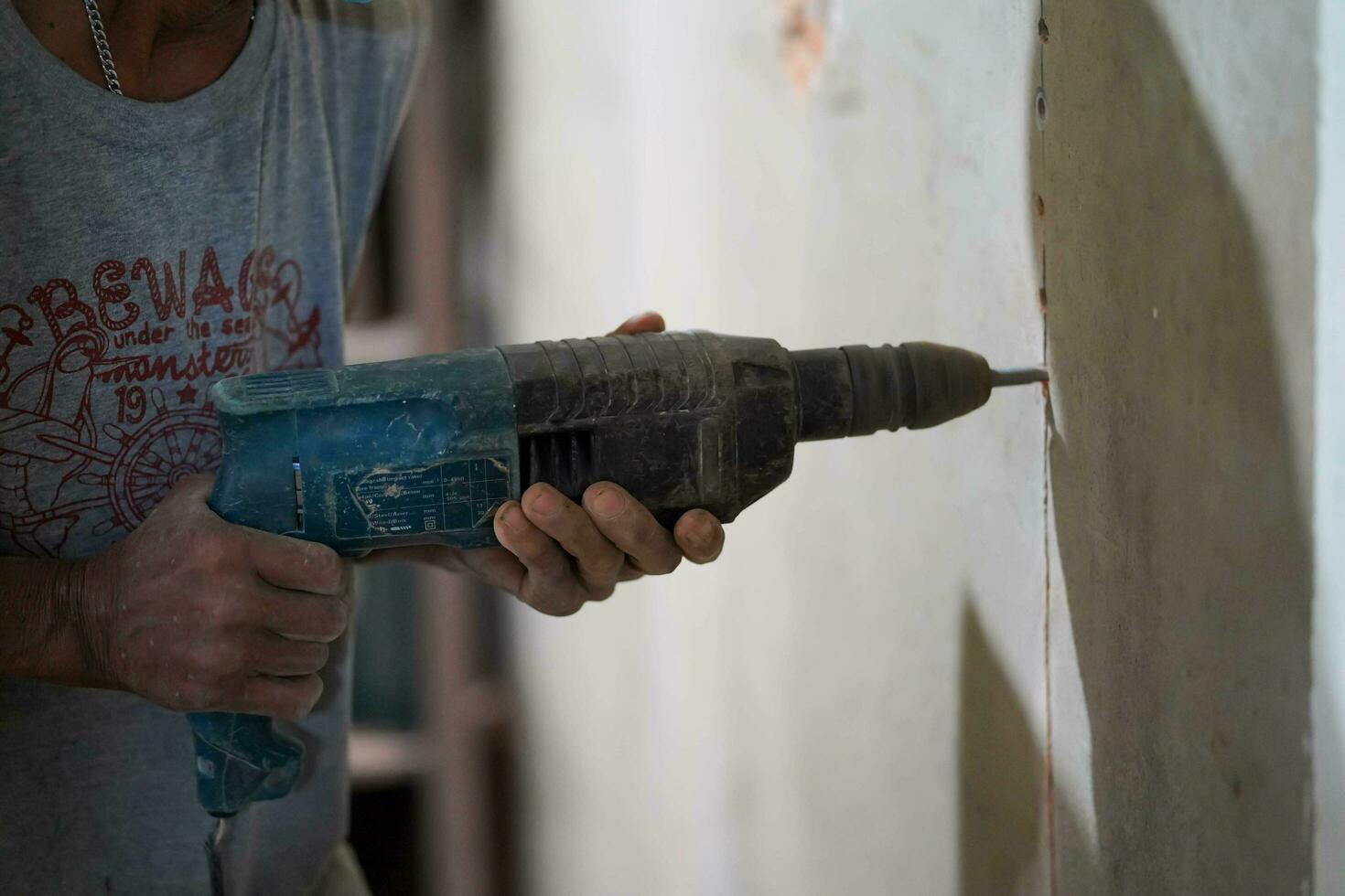 Closeup hands of builder holding an electric drill is drilling a hole in the wall at construction site. photo