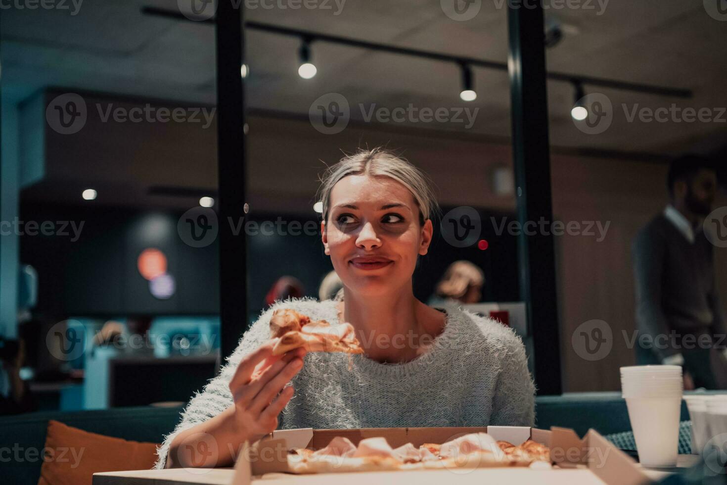un mujer comiendo Pizza en el oficina foto