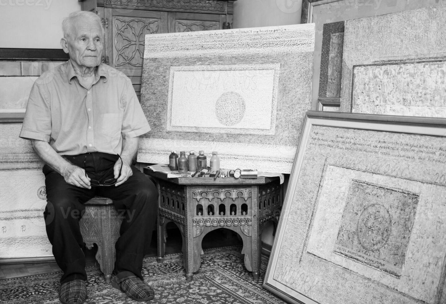 an older man is standing in front of a painting photo