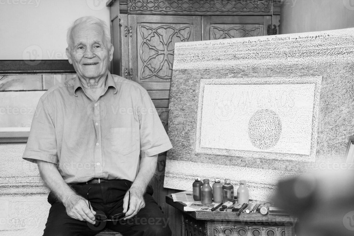 an older man is standing in front of a painting photo