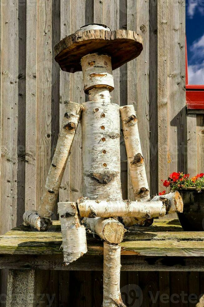 a wooden man with a hat sitting on a bench photo