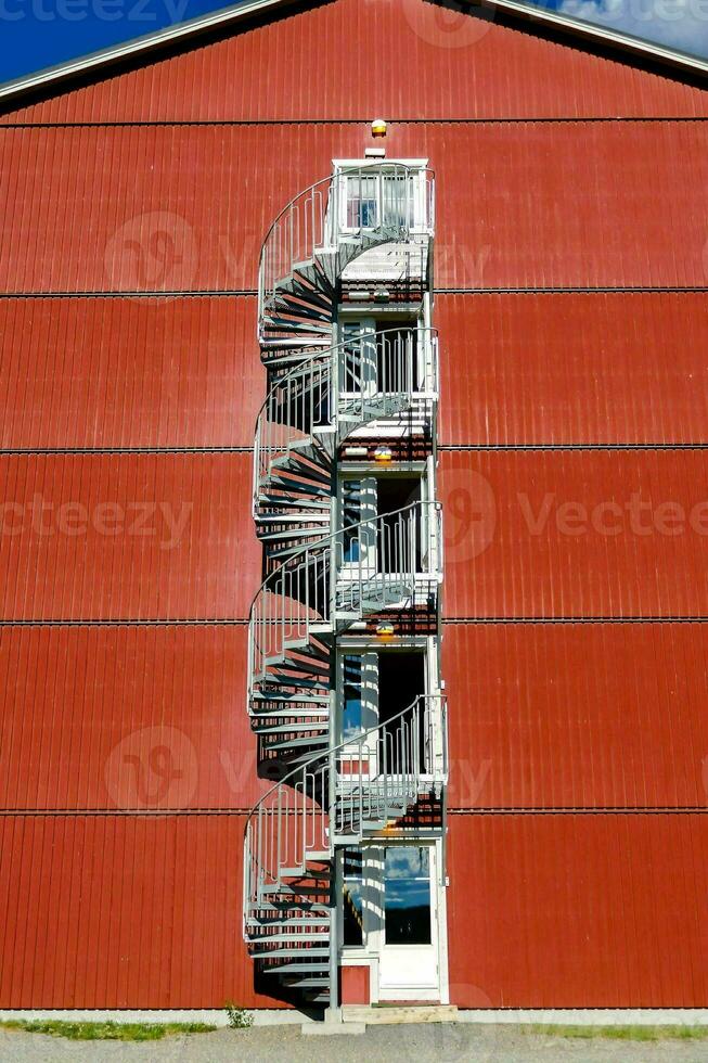 un espiral escalera en el lado de un rojo edificio foto