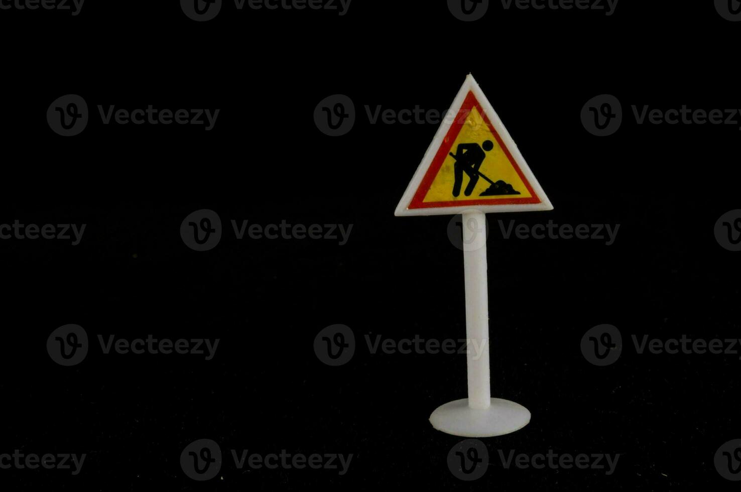 a warning sign with a person digging on a black background photo