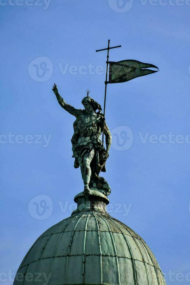 a statue of a man holding a flag on top of a dome photo