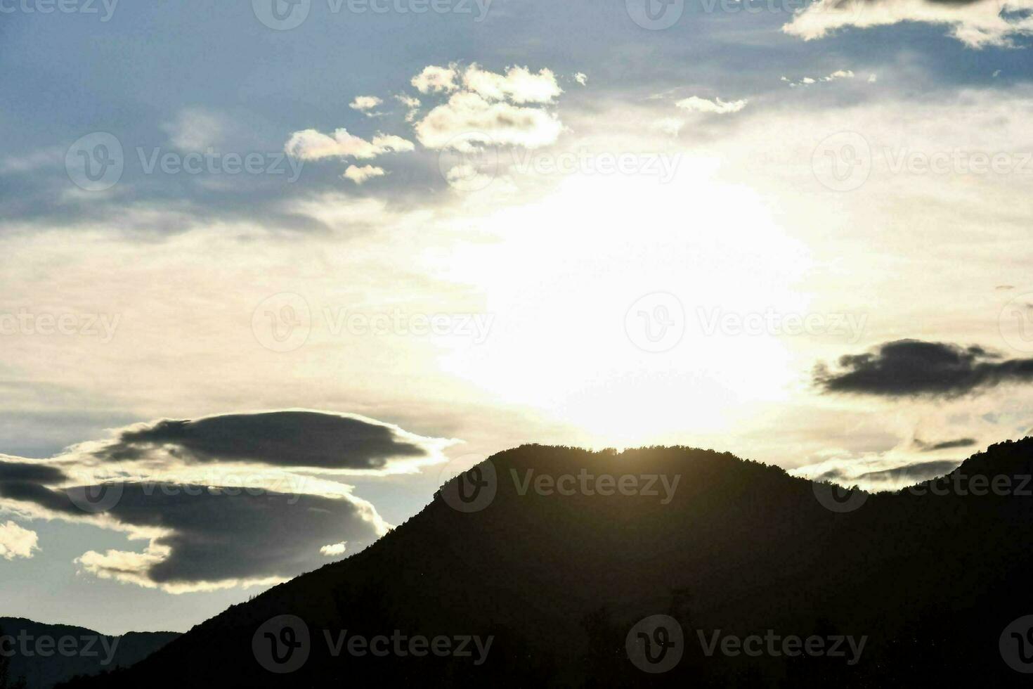 the sun is setting behind a mountain range photo