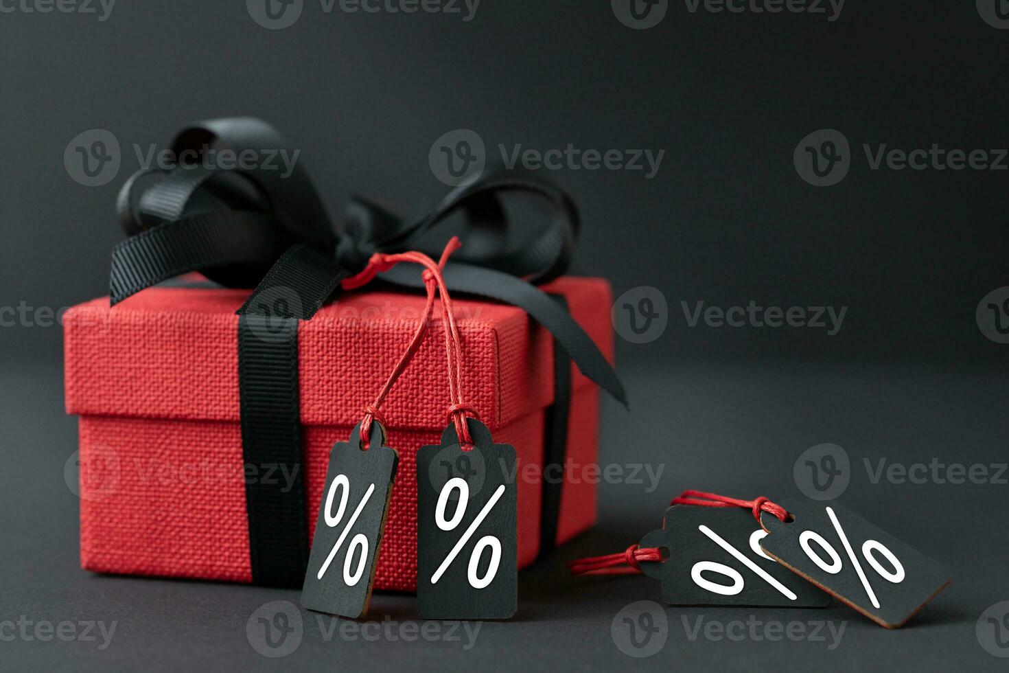 Red gift box with labels on black background photo