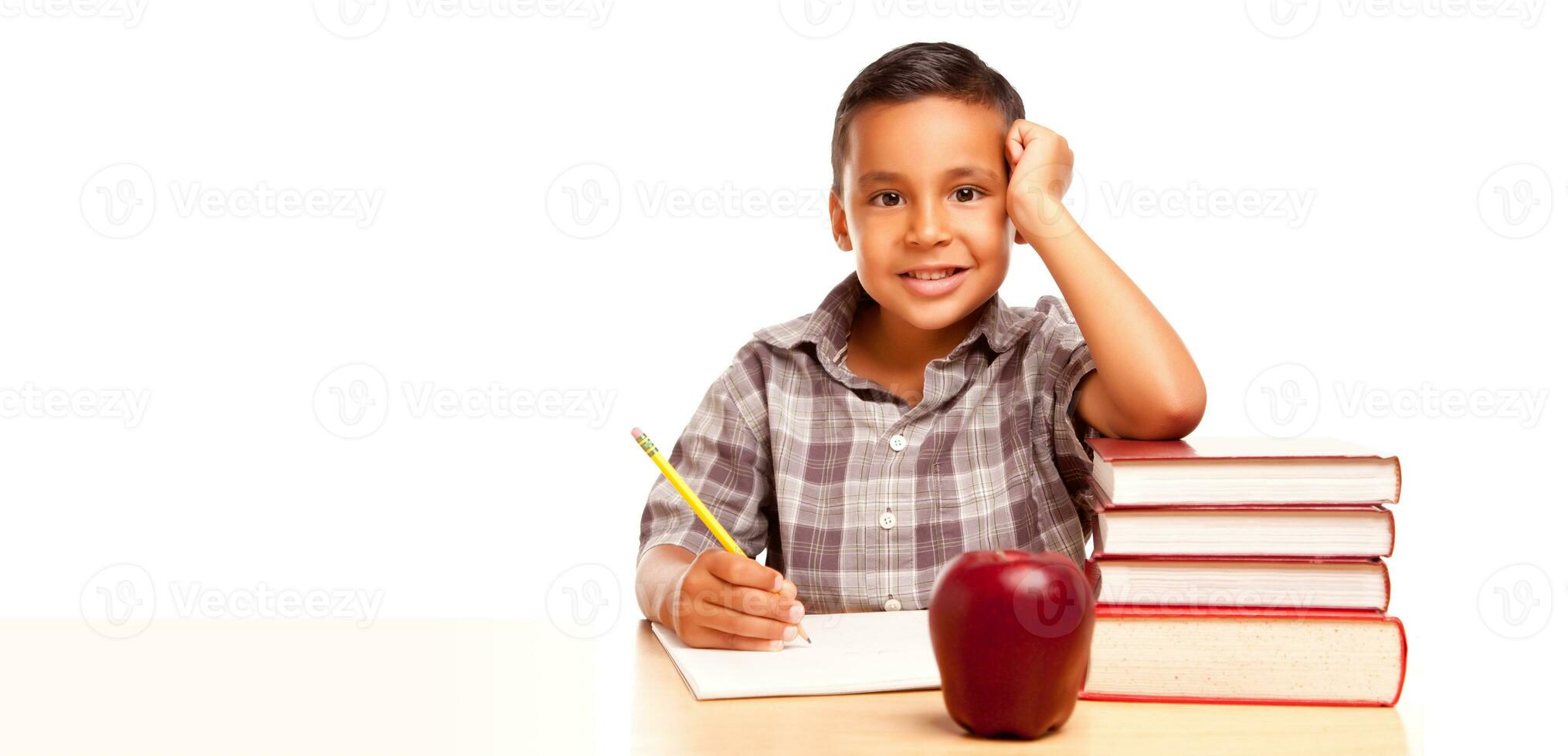 contento joven Hispano colegio chico a escritorio con libros y manzana aislado en un blanco antecedentes. foto