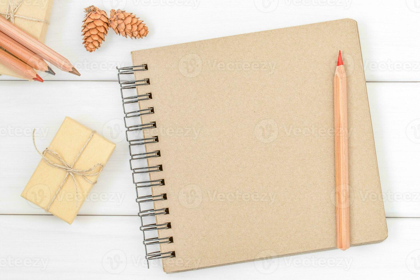 Notebook with red pencil, ecological gift and cones on the white bbackground photo