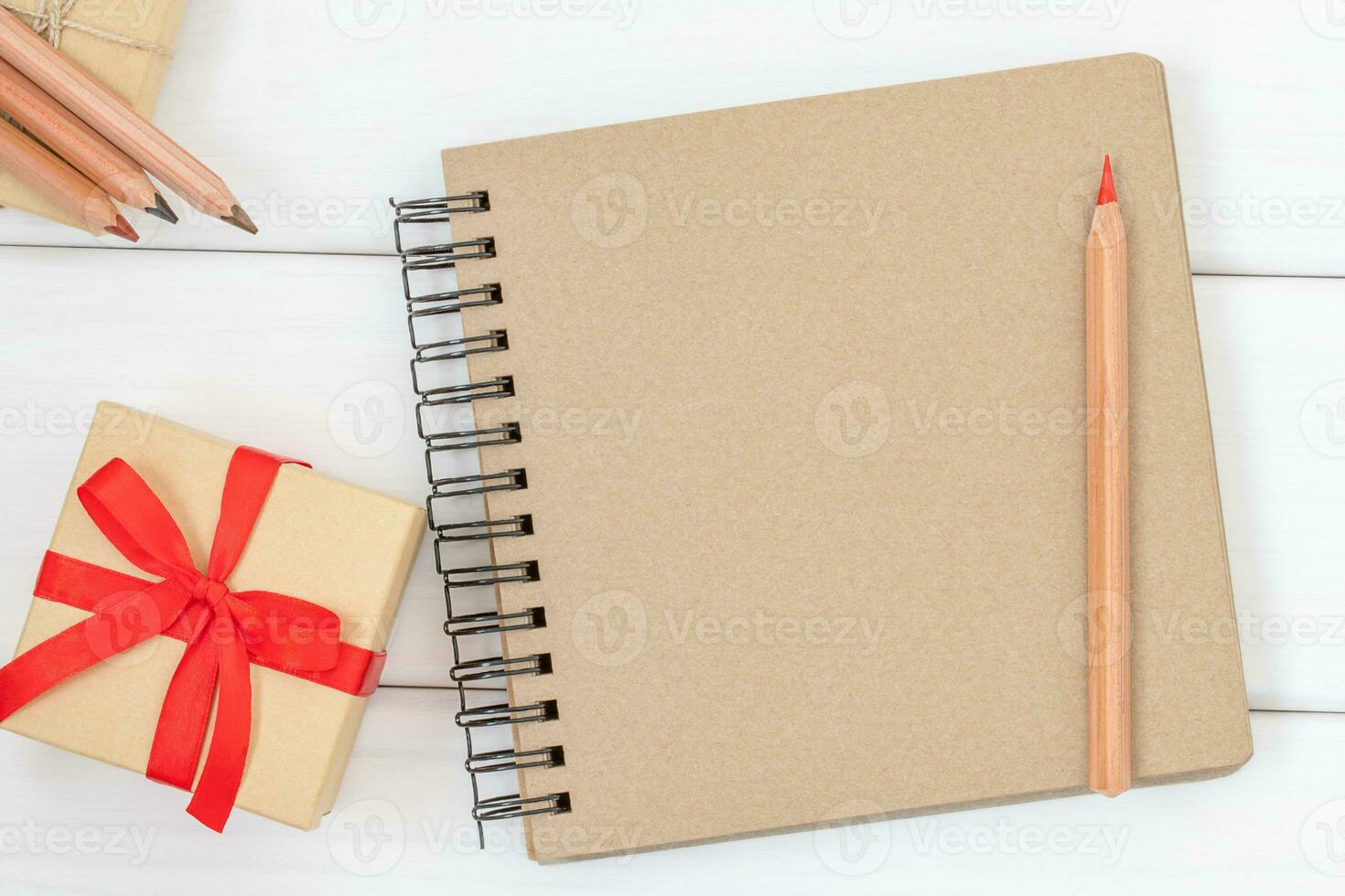 Notebook with red pencil and holiday box on the white background photo