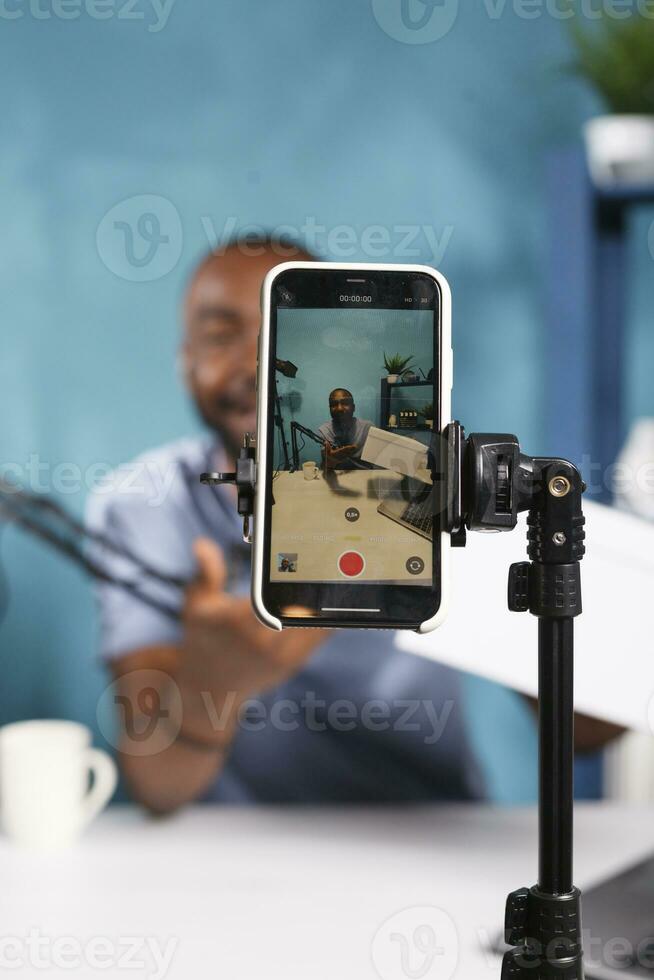 Blogger broadcasting giveaway on smartphone screen closeup. African american internet influencer announcing online contest for brand promotion marketing campaign using mobile phone photo