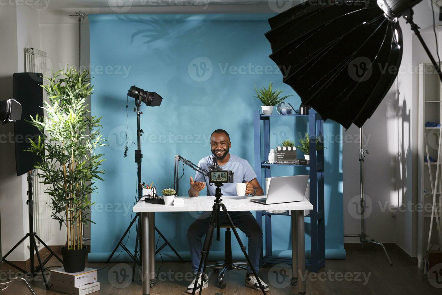 Blogger connecting with subscribers while speaking in microphone and live streaming in studio. Smiling african american vlogger looking at professional camera while recording video photo