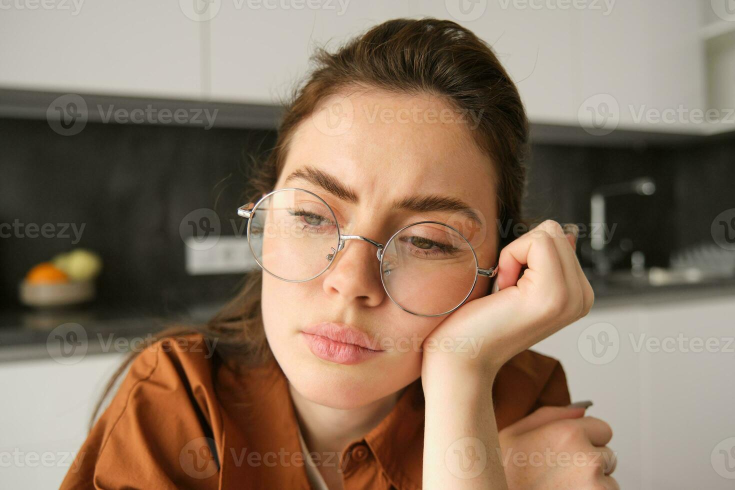 Close up portrait of woman in glasses with concerned, sad face, looking upset, troubled expression, sitting at home photo