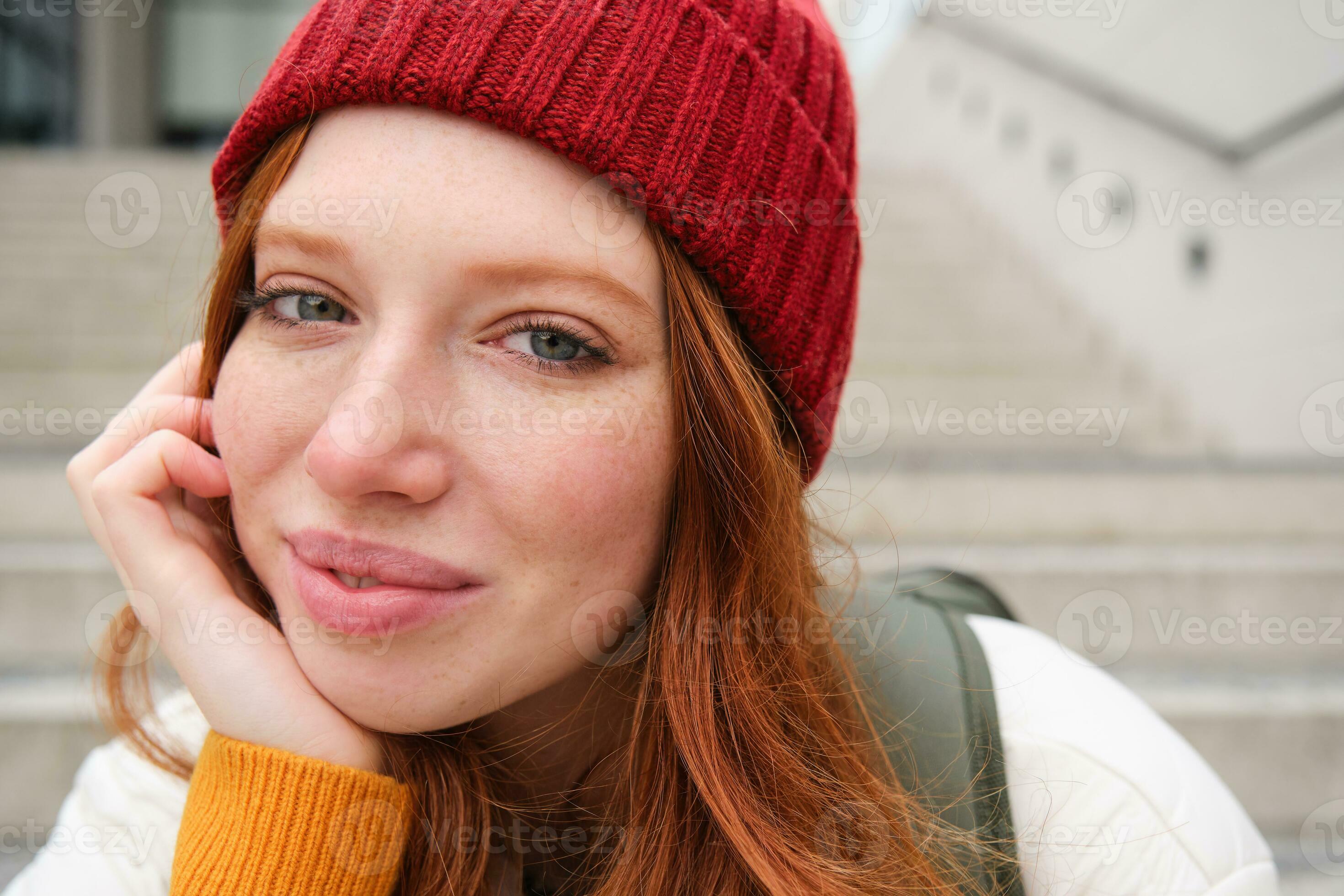 Close up portrait of beautiful redhead girl in red hat, urban woman