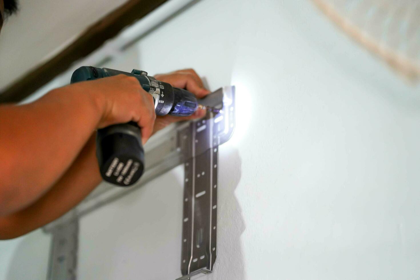 Closeup hands of builder holding an electric drill is drilling a hole in the wall for install air condition at construction site. photo